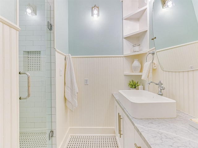 bathroom with tile patterned floors, a wainscoted wall, a shower stall, and vanity
