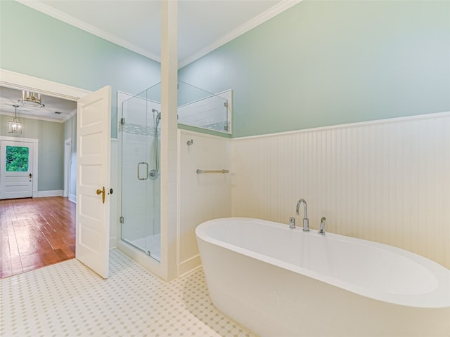 full bathroom with crown molding, a wainscoted wall, a shower stall, and a freestanding tub