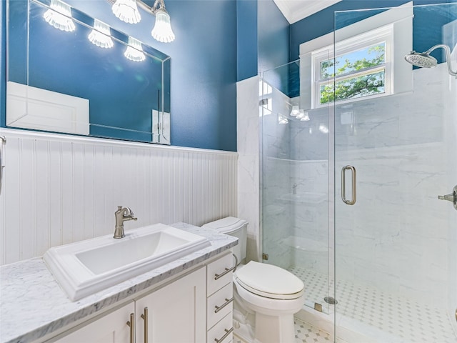 full bath with vanity, crown molding, toilet, a wainscoted wall, and a marble finish shower