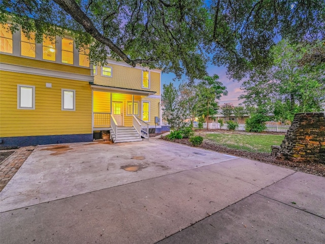 back house at dusk featuring a porch