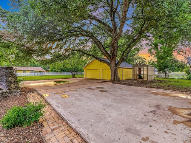 yard at dusk featuring a garage and an outdoor structure