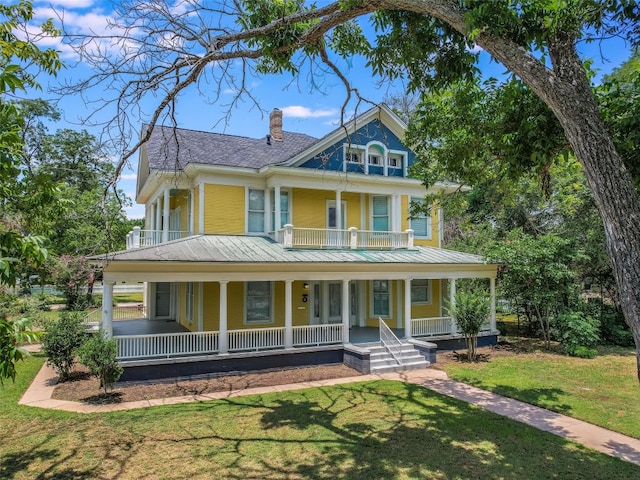view of front facade with a porch, a chimney, a front yard, and a balcony