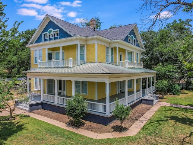 view of front of home with a front yard, a balcony, and covered porch