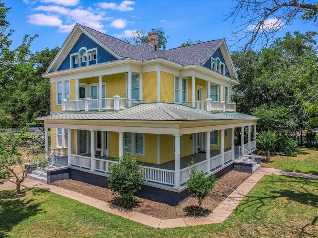 1302 Hill St, Bastrop, TX 78602 - view of front of property with covered porch, a balcony, a chimney, and a front lawn