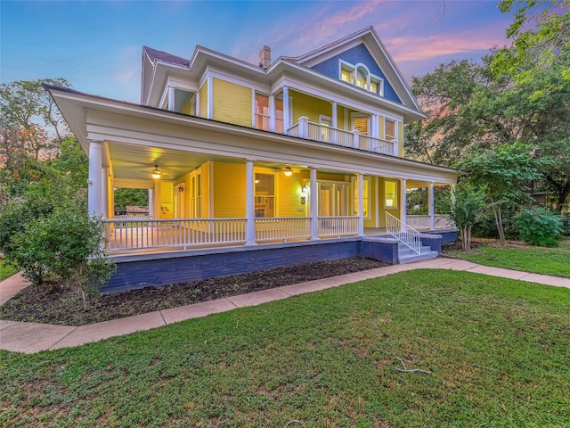 view of front of house featuring a front yard, ceiling fan, covered porch, and a balcony