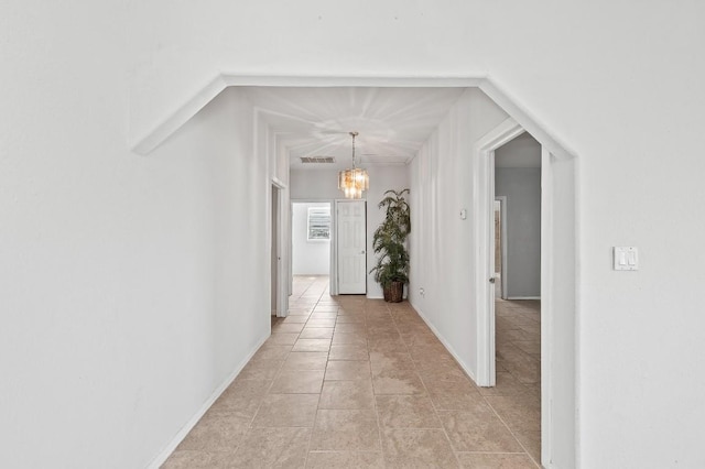 hallway with light tile patterned floors and a chandelier