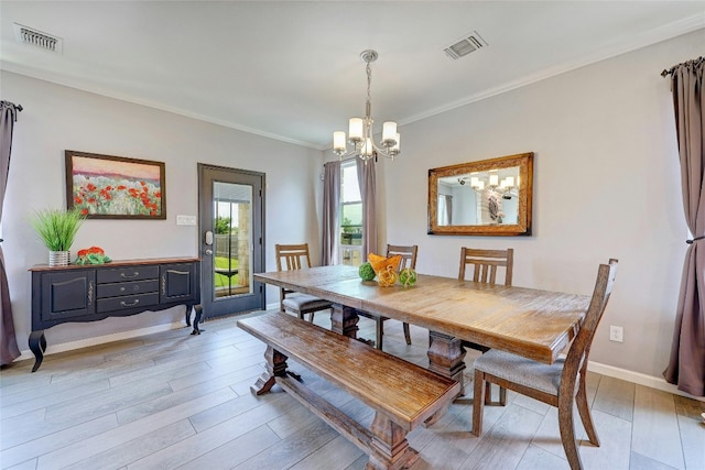 dining space with light hardwood / wood-style flooring, ornamental molding, and an inviting chandelier