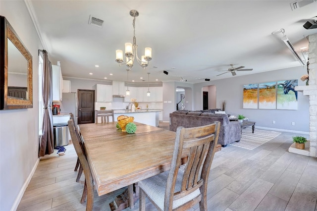 dining room featuring ceiling fan with notable chandelier, light hardwood / wood-style floors, ornamental molding, and sink