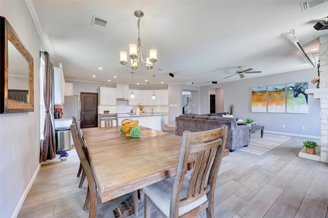 31451 Kingsway Rd, Georgetown, TX 78628 - dining space featuring arched walkways, a ceiling fan, light wood-type flooring, ornamental molding, and a chandelier