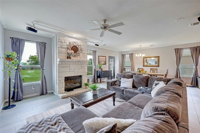 living room featuring a stone fireplace, light wood-type flooring, ceiling fan with notable chandelier, and ornamental molding