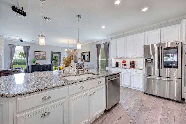 31451 Kingsway Rd, Georgetown, TX 78628 - kitchen with appliances with stainless steel finishes, crown molding, a chandelier, white cabinets, and an island with sink