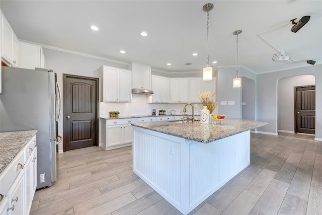 kitchen featuring stainless steel refrigerator, light hardwood / wood-style flooring, white cabinets, and an island with sink