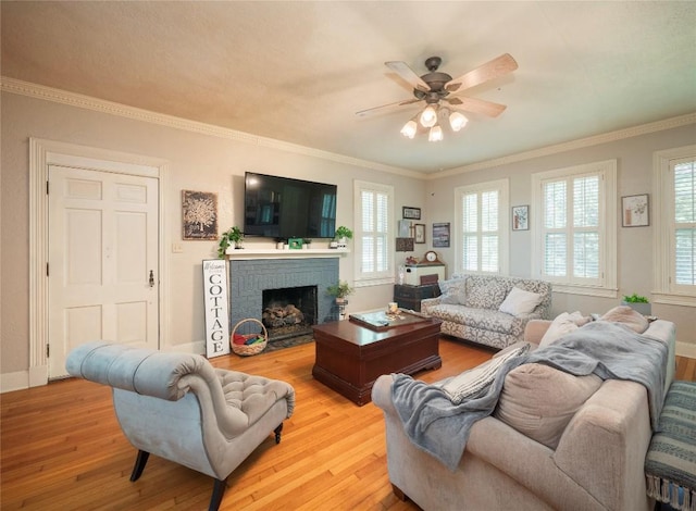 living room with ceiling fan, light hardwood / wood-style flooring, ornamental molding, and a brick fireplace