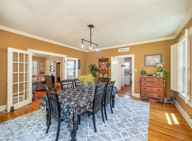 dining space featuring hardwood / wood-style floors, french doors, and ornamental molding