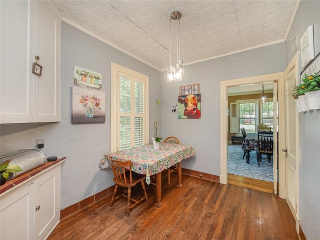 dining room with a notable chandelier, ornamental molding, and dark wood-type flooring