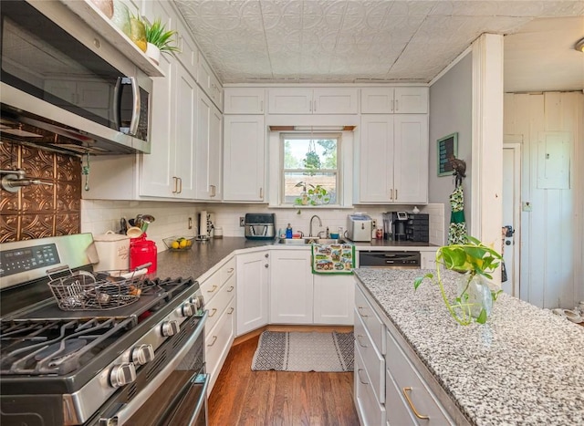 kitchen featuring light stone countertops, stainless steel appliances, sink, dark hardwood / wood-style floors, and white cabinetry