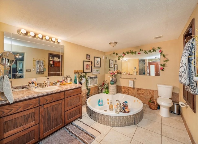 bathroom featuring tiled tub, tile patterned flooring, vanity, and a textured ceiling