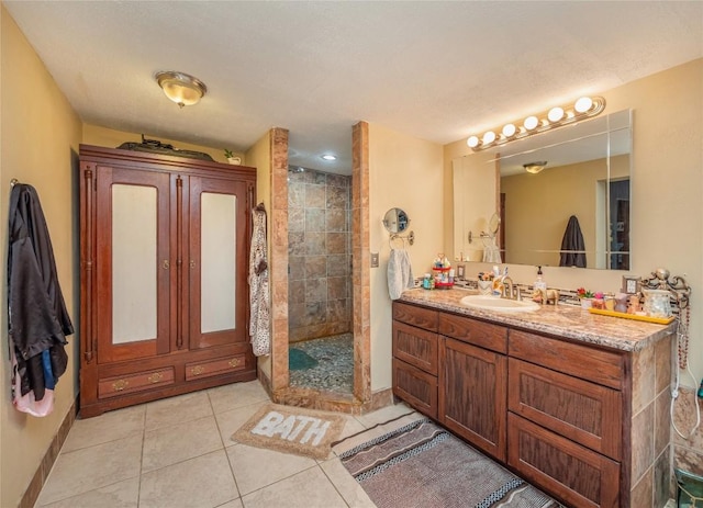 bathroom with tile patterned floors, vanity, tiled shower, and a textured ceiling