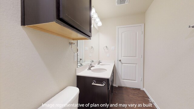 bathroom featuring large vanity, wood-type flooring, toilet, and dual sinks