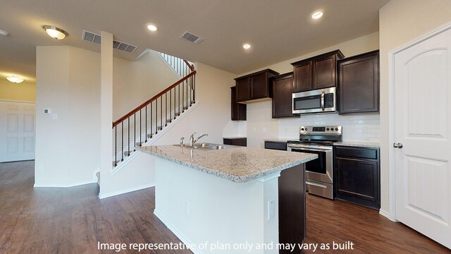 kitchen featuring tasteful backsplash, dark wood-type flooring, sink, a kitchen island with sink, and appliances with stainless steel finishes