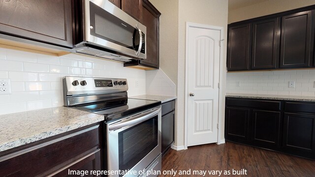 kitchen with appliances with stainless steel finishes, dark hardwood / wood-style floors, dark brown cabinets, light stone counters, and backsplash