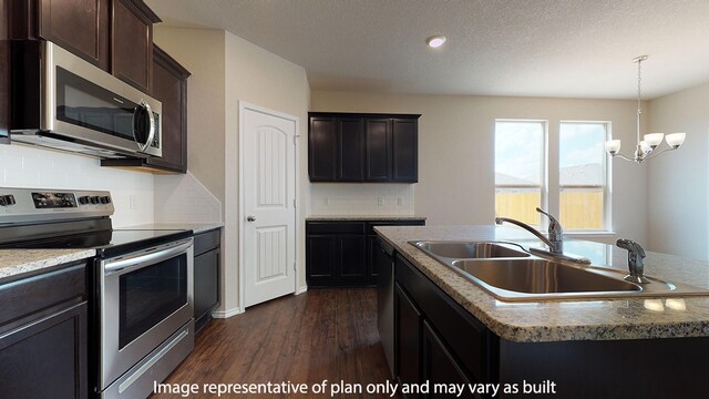 kitchen with dark hardwood / wood-style floors, tasteful backsplash, a center island with sink, sink, and appliances with stainless steel finishes