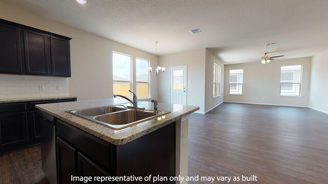 kitchen featuring tasteful backsplash, dark wood-type flooring, hanging light fixtures, sink, and a kitchen island with sink