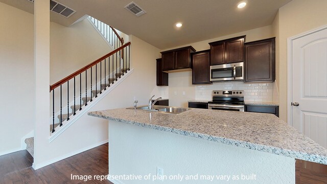 kitchen with a kitchen island, dark hardwood / wood-style flooring, appliances with stainless steel finishes, sink, and tasteful backsplash