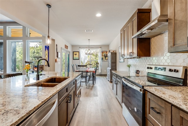 kitchen featuring appliances with stainless steel finishes, sink, wall chimney range hood, and light stone counters