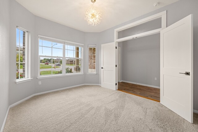 unfurnished bedroom featuring carpet floors, multiple windows, and a chandelier