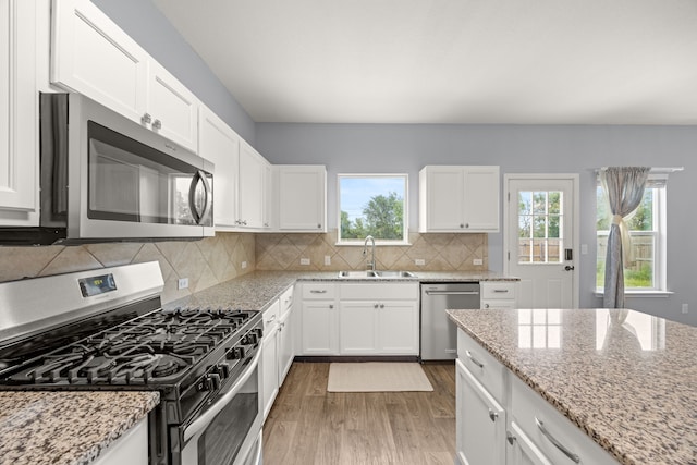 kitchen with stainless steel appliances, white cabinetry, sink, and tasteful backsplash