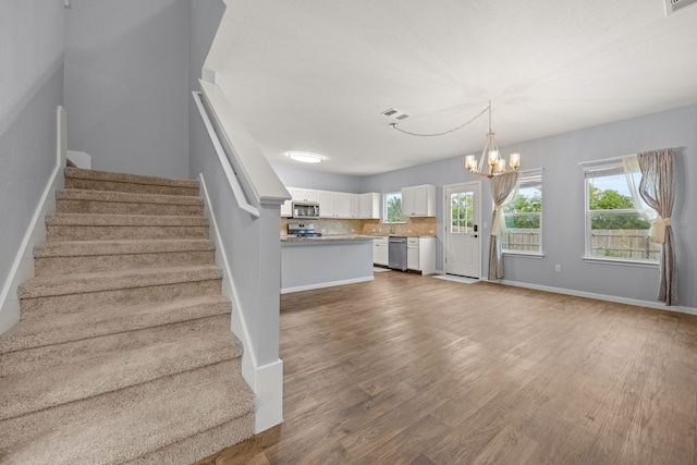 staircase with a notable chandelier and hardwood / wood-style floors