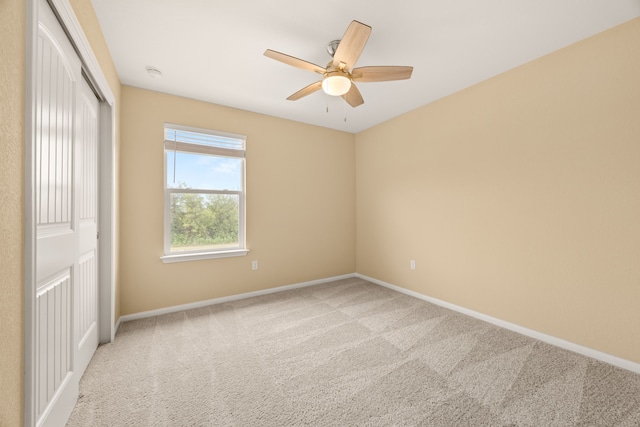 empty room featuring ceiling fan and light colored carpet