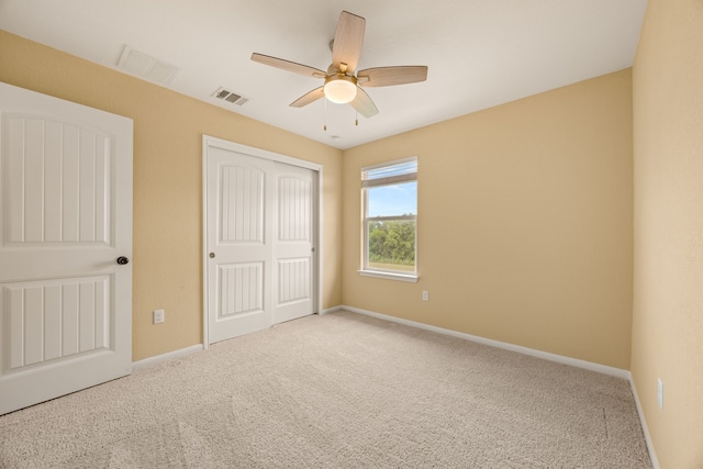 unfurnished bedroom with ceiling fan, light colored carpet, and a closet