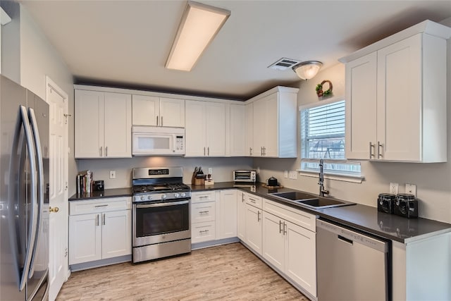 kitchen with light hardwood / wood-style floors, white cabinetry, sink, and appliances with stainless steel finishes