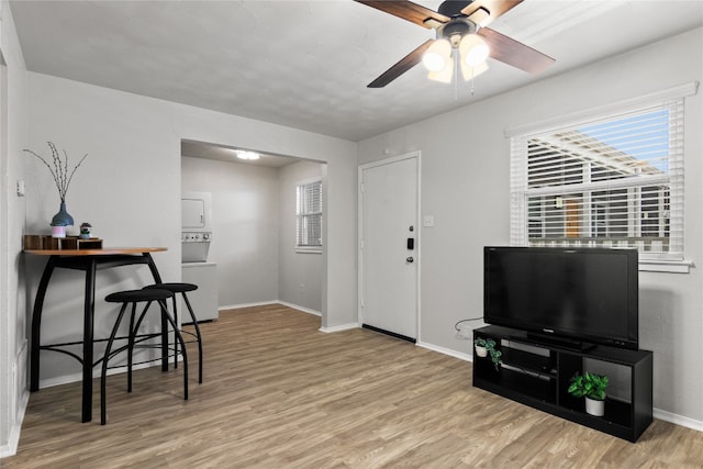 interior space with light hardwood / wood-style flooring, ceiling fan, and stacked washer / drying machine