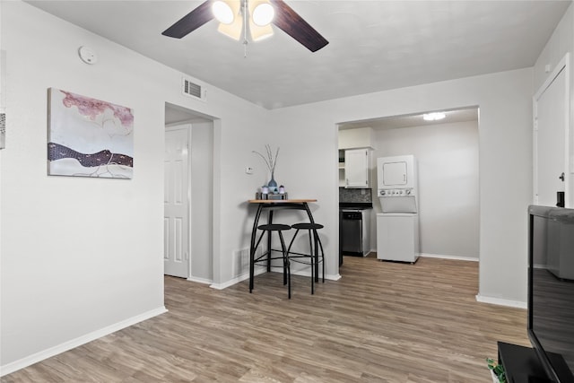 interior space featuring light wood-type flooring, stacked washing maching and dryer, and ceiling fan