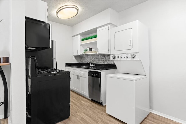 kitchen featuring stacked washer and dryer, dishwasher, black gas range, tasteful backsplash, and white cabinets