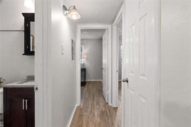 hallway featuring a textured ceiling and light hardwood / wood-style floors