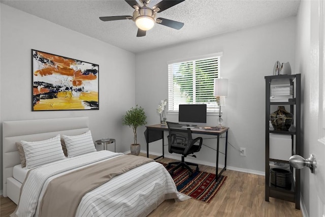 bedroom featuring ceiling fan, light hardwood / wood-style flooring, and a textured ceiling