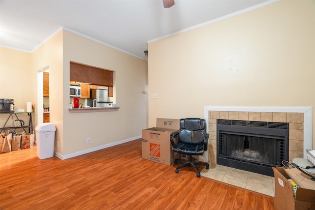 office space featuring crown molding, hardwood / wood-style flooring, a fireplace, and ceiling fan