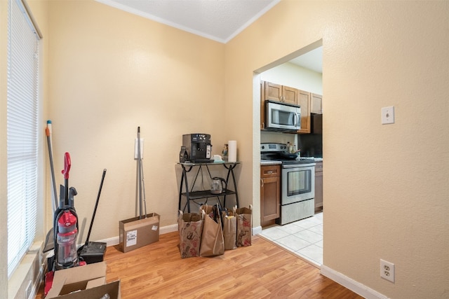 interior space featuring appliances with stainless steel finishes, ornamental molding, and light tile flooring