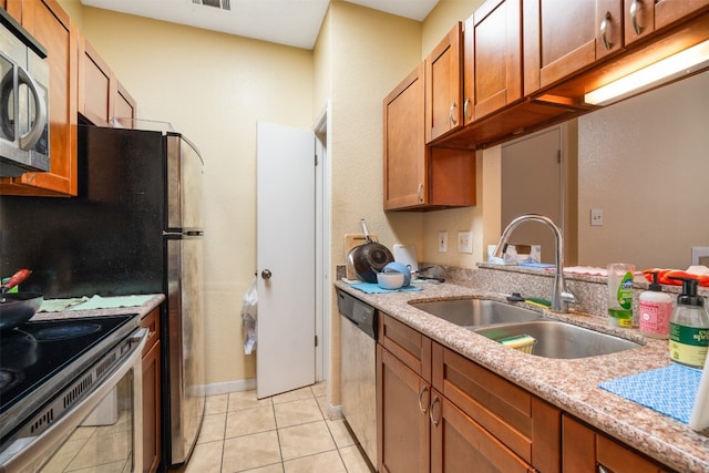 kitchen with light stone counters, appliances with stainless steel finishes, sink, and light tile floors