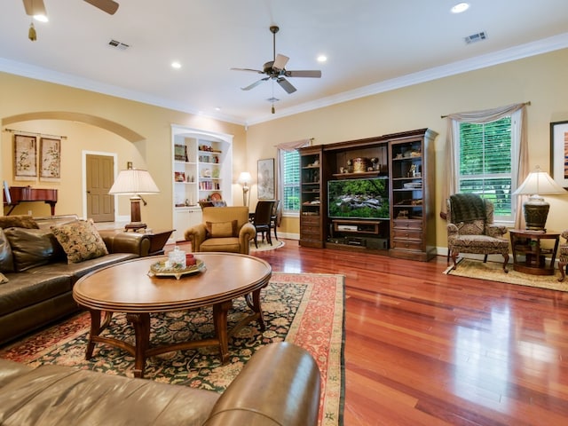 living room with hardwood / wood-style floors, ceiling fan, built in features, and ornamental molding