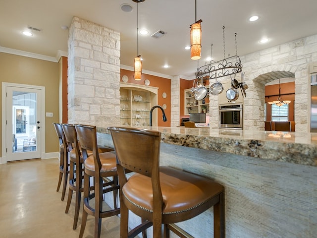 bar featuring pendant lighting, stainless steel oven, crown molding, built in features, and light stone counters