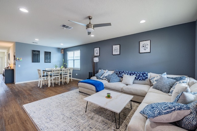 living room with ceiling fan, dark wood-type flooring, and a textured ceiling