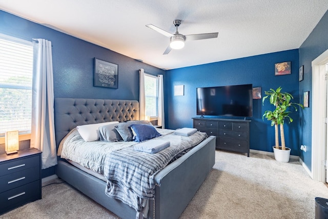 bedroom with a textured ceiling, light colored carpet, and ceiling fan