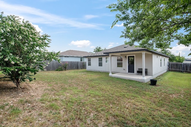 back of house with a lawn and a patio