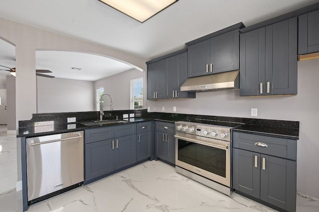 kitchen with ceiling fan, sink, stainless steel appliances, and dark stone countertops