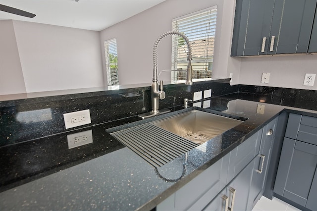 kitchen with a healthy amount of sunlight, sink, dark stone countertops, and gray cabinets